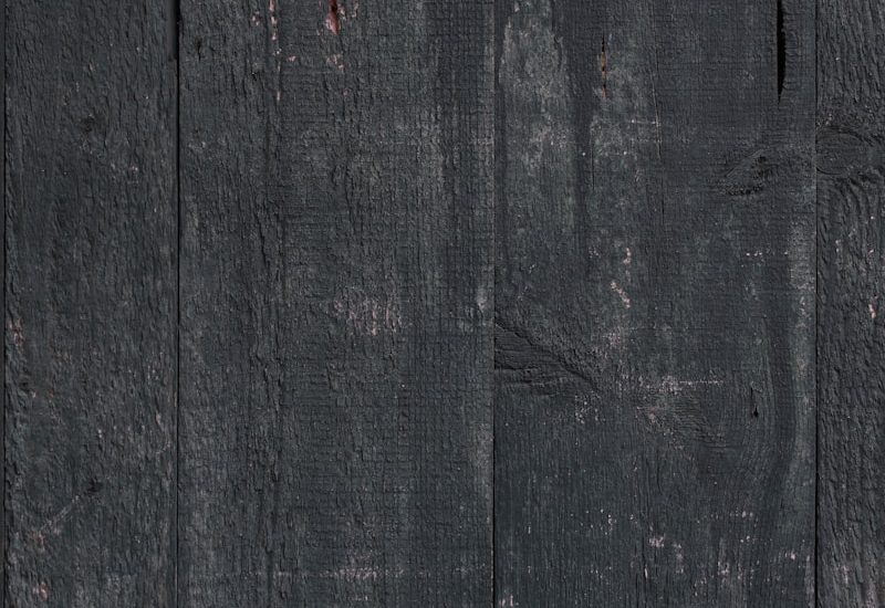 a black wooden wall with peeling paint on it